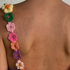 the back of a woman's top with crocheted flowers attached to it