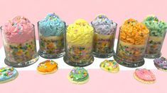 there are many decorated cookies in the glass vases on the table with pink background