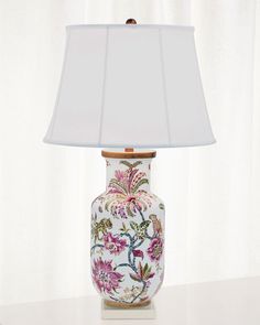 a lamp that is on top of a table with a flowered vase underneath it