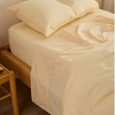 a bed with two pillows on top of it next to a small table and chair