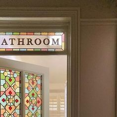 a stained glass door with the word bathroom on it's side and an open window