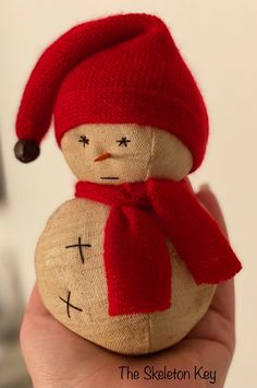 a hand holding a stuffed snowman wearing a red hat and scarf