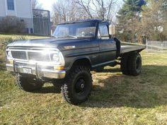 an old pickup truck parked in the grass near a house and fenced in yard