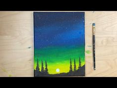 an acrylic painting with trees and the moon in the sky, on top of a wooden table