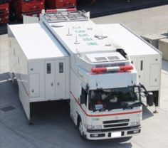 a large white truck parked next to other red and white trucks in a parking lot