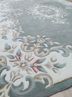 an area rug with flowers and scrolls on the top in blue, beige and white colors