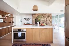 a kitchen with an oven, sink and counter top in front of a stone wall