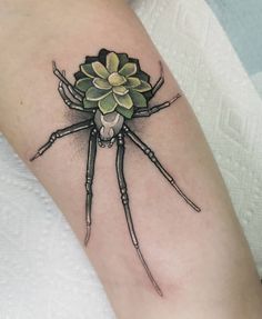 a spider with a flower on it's back leg is shown in this tattoo design