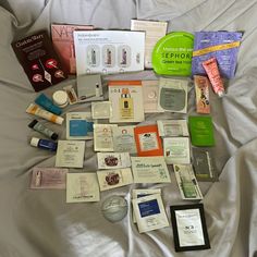 the contents of a travel bag laid out on top of a white bed spreaded in sheets