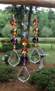 a wind chime hanging from a tree branch in the park with trees and bushes behind it