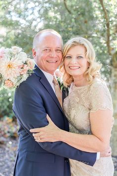 a man and woman hugging each other in front of trees