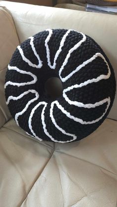 a black and white knitted pillow sitting on top of a couch next to a book