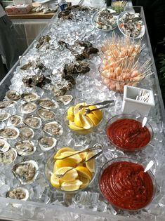 a buffet table filled with oysters, lemon wedges and ketchup sauce