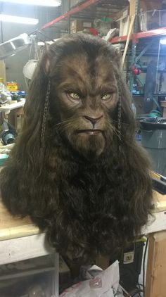 a man with long hair and a beard wearing a chewy bear mask on top of a table