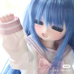 a close up of a doll with blue hair and bangs holding her hand out to the side