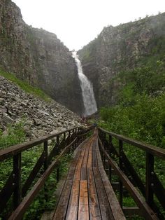 a wooden bridge with a waterfall in the background