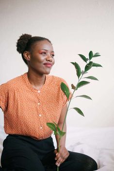 a woman sitting on a bed holding a plant