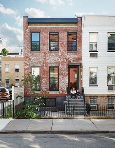 two people are sitting on the front porch of this brick and stone townhouse in new york city