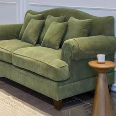 a green couch sitting on top of a hard wood floor next to a white wall