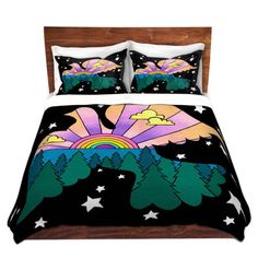 a bed covered in a black comforter with trees and mountains painted on the cover