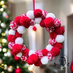 a red and white pom - pom wreath hanging from a christmas tree