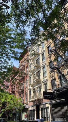 people are walking down the sidewalk in front of some tall buildings with balconies