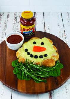 a wooden plate topped with food on top of a white wood table next to a jar of ketchup