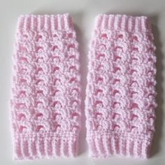 two pink crocheted mittens sitting next to each other