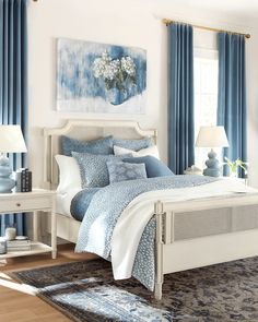 a bedroom with blue curtains and white bedding