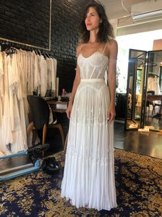 a woman standing in front of a rack of wedding gowns