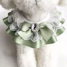 a white teddy bear wearing a green and white dress