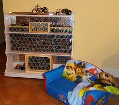 there is a book shelf with toys on it and a dog bed in front of it