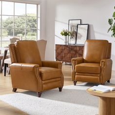 two brown leather chairs sitting on top of a white rug