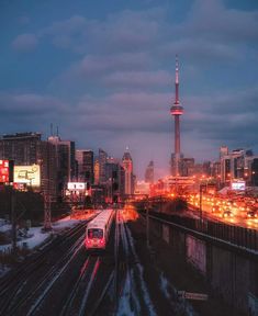 a train traveling through a city next to tall buildings and traffic lights at night time