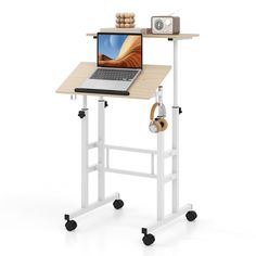 a laptop computer sitting on top of a wooden desk next to a white metal frame