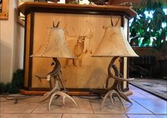 two deer antler lamps sitting on top of a table next to a lamp shade