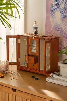 a wooden table topped with a small cabinet next to a potted plant