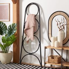 a bathroom with a towel rack, potted plant and two mirrors on the wall