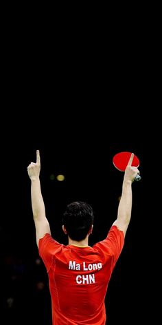 a man holding a red frisbee on top of a tennis racquet