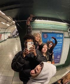 a man taking a selfie with his friends in a mirror at the subway station