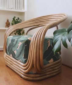 a chair made out of wicker sitting on top of a hard wood floor next to a potted plant