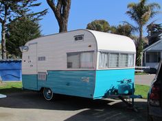 a blue and white trailer parked next to a tree