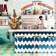 a man standing behind a counter in a restaurant with blue and white tiles on the floor