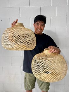 a man holding two large baskets in front of his face and smiling at the camera