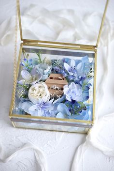 a glass box filled with flowers on top of a bed