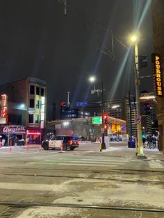 the city street is busy with cars and people on it at night time, as well as traffic lights