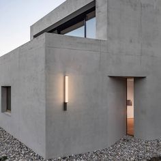 an exterior view of a concrete building with two lights on the outside and one light on the inside