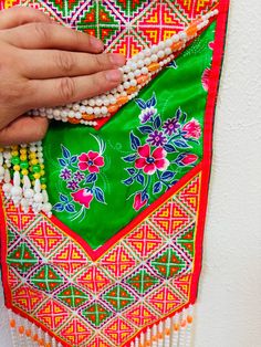 a person is holding some beads in their hand while wearing a green and red dress