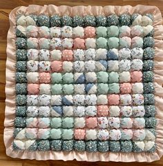 a baby blanket made out of cloths on top of a wooden floor with pink and blue