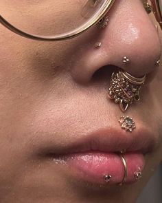 a close up of a person wearing glasses and piercings on their nose with gold jewelry